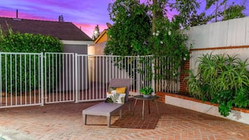 Un patio con piscina, un recinto bianco e una sedia a sdraio.