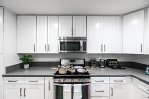 Cozinha moderna com armários brancos, eletrodomésticos de aço inoxidável e fogão a gás.