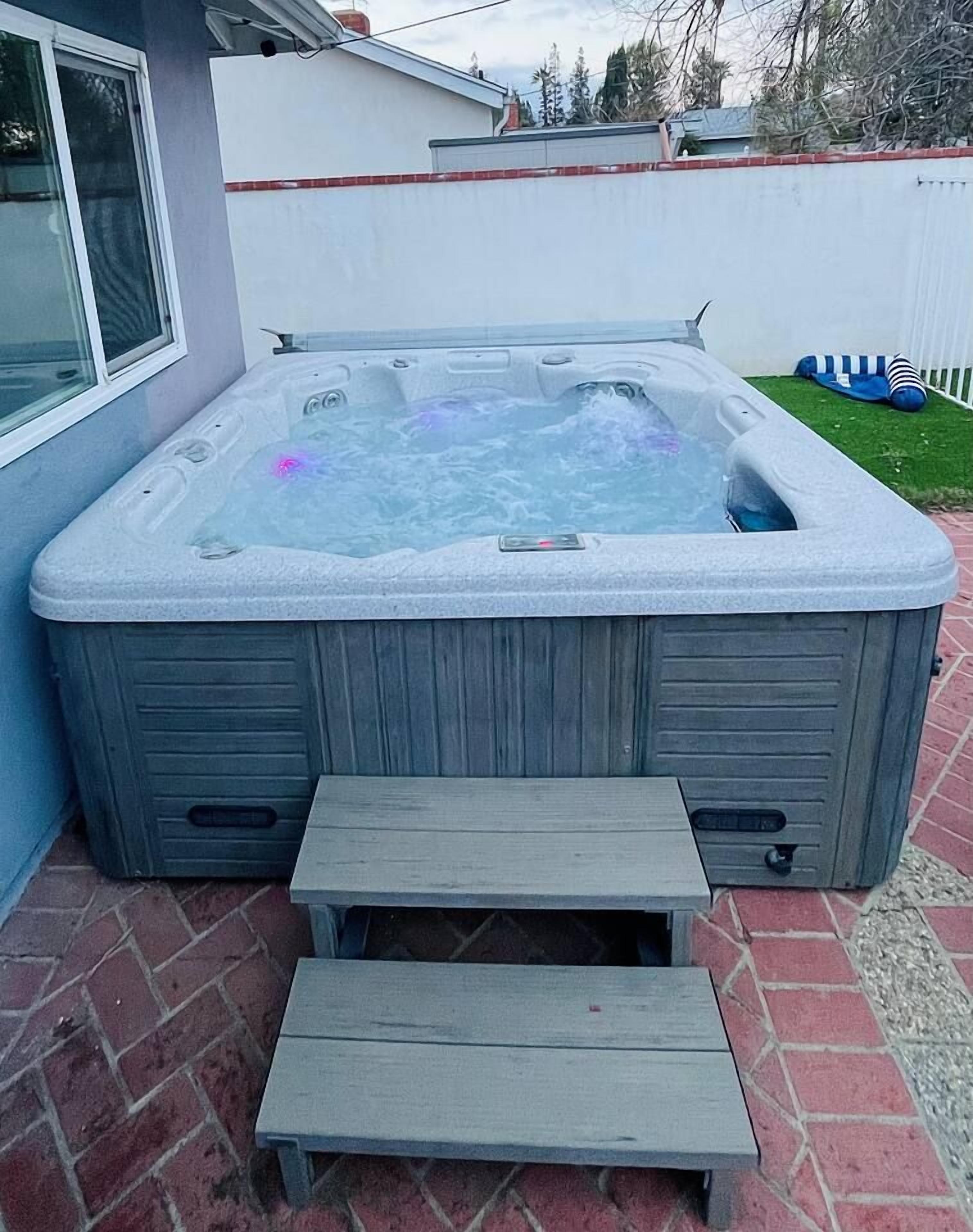 A hot tub with steps leading up to it, placed on a brick patio.
