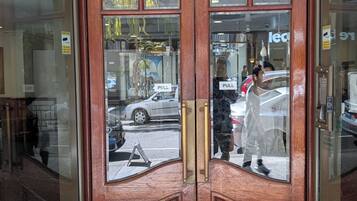 Una puerta de madera giratoria con paneles de vidrio, piso de baldosas y un letrero que indica 'PULL'.