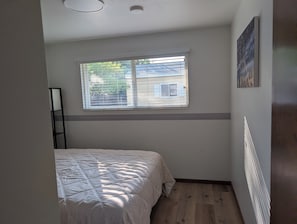 A bedroom with a bed, a window, and a radiator.