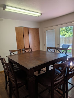 A dining area with a wooden table and chairs, a sliding door leading to a patio, and a ceiling light fixture.