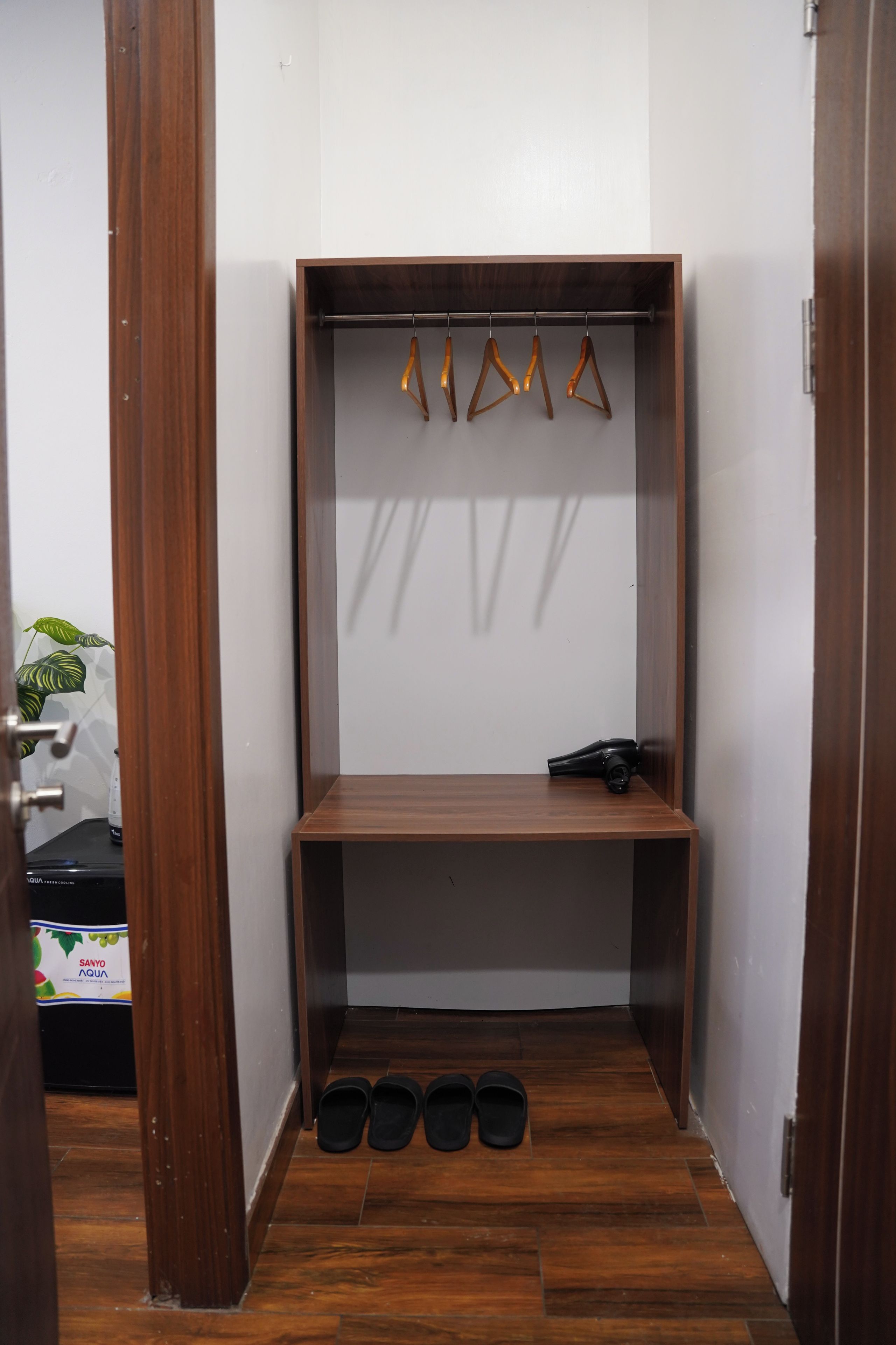 A small closet with wooden doors, a hanging rod, and a shelf.