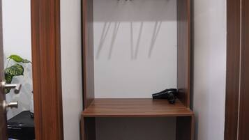 A small closet with wooden doors, a hanging rod, and a shelf.