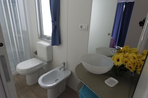 Ein Badezimmer mit Toilette, Bidet, Waschbecken und Spiegel.