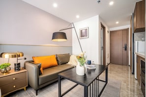 Una sala de estar moderna con un sofá, una mesa de centro, una lámpara y un florero con flores.