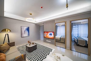 A modern hotel room with a sofa, a coffee table, a TV, and a bed with a view. - Yu An Hotel (Guangzhou)