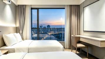 A hotel room with a large window, a bed, a desk, and a projector.