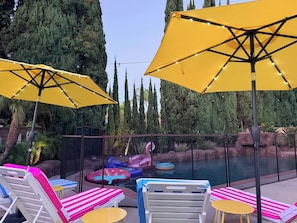 Un espace piscine équipé de chaises longues, de jeux gonflables et de parasols jaunes.