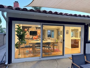Un patio cubierto con área de comedor, puertas correderas de vidrio y vistas a una cocina y sala de estar.