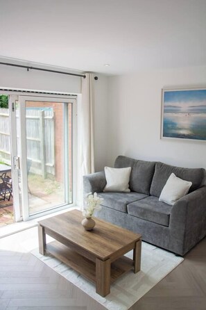 Ein Wohnzimmer mit grauem Sofa, einem Holztisch und einem Bild an der Wand.