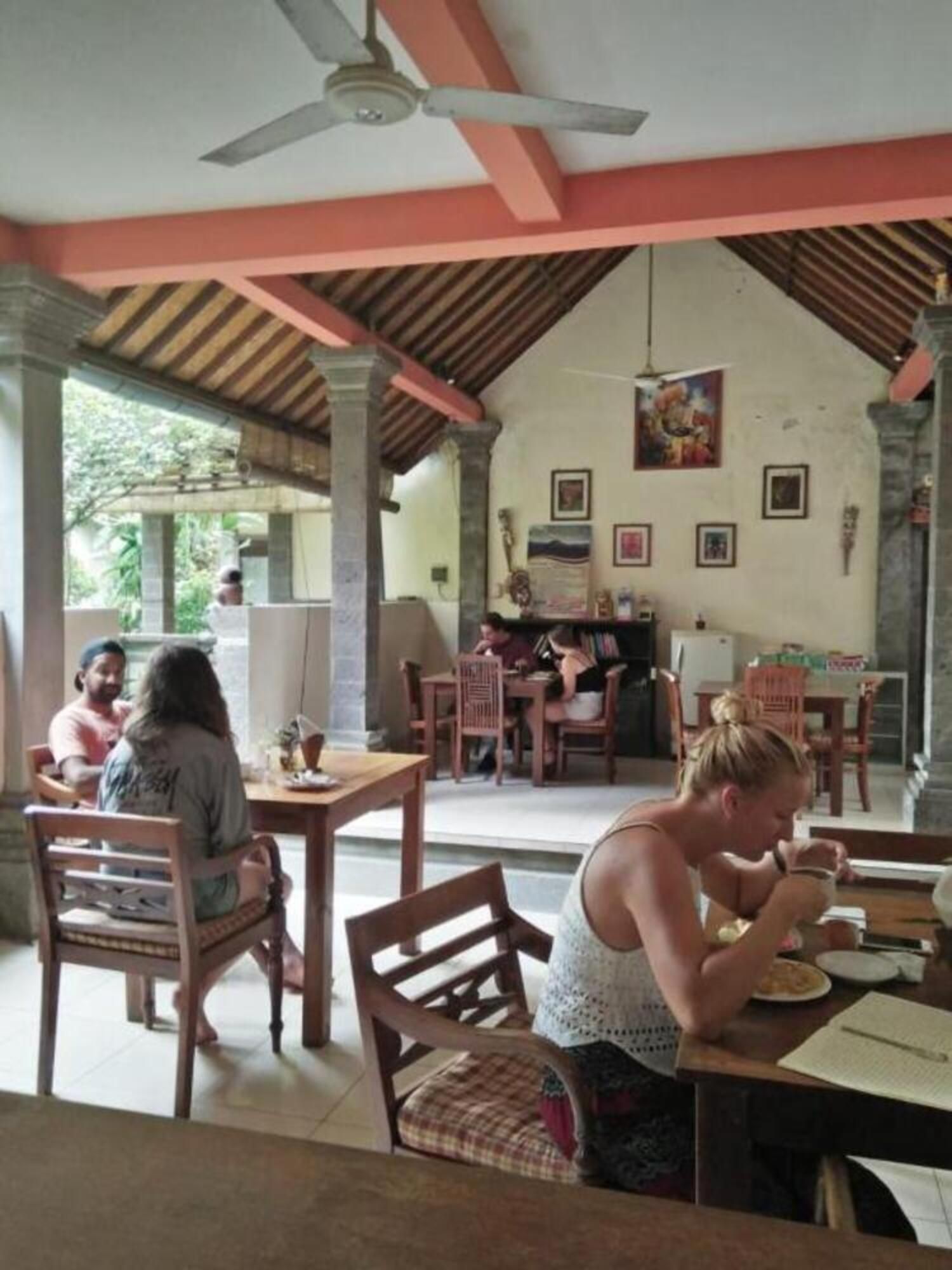 A dining area with wooden furniture and a high ceiling with a fan.