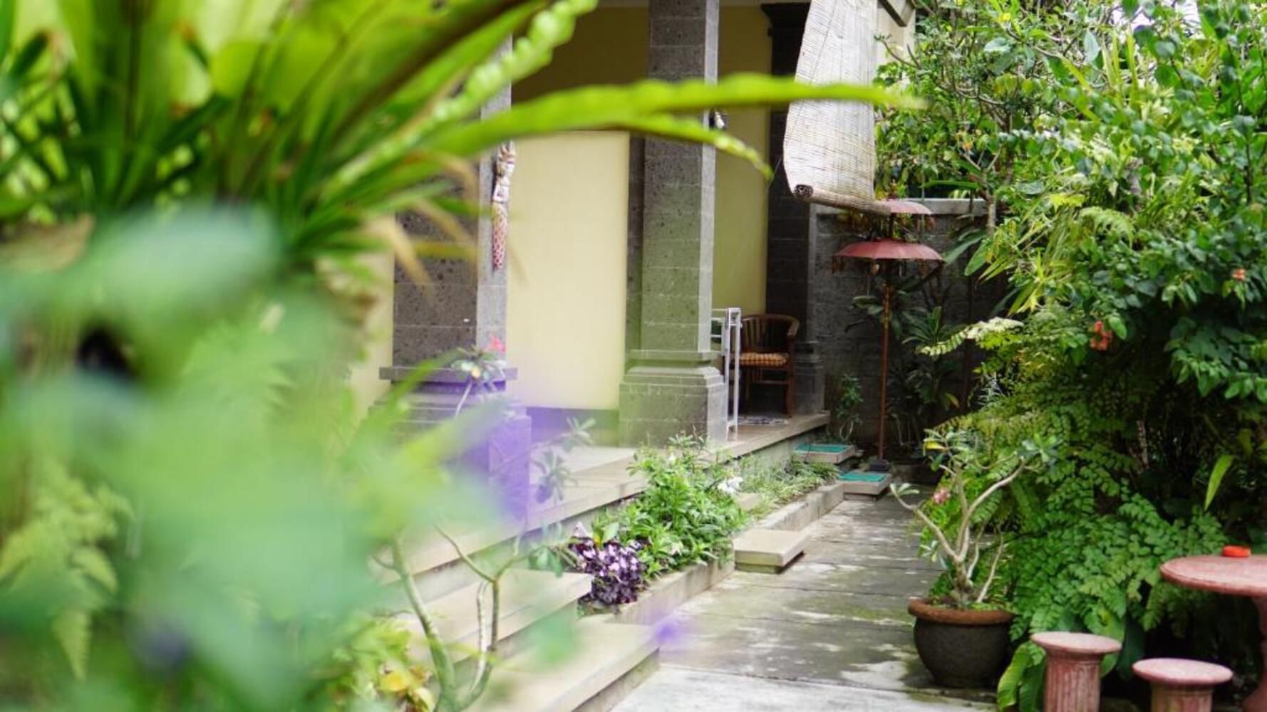 A garden pathway leading to a building with a stone wall and a small seating area with a table and chairs.