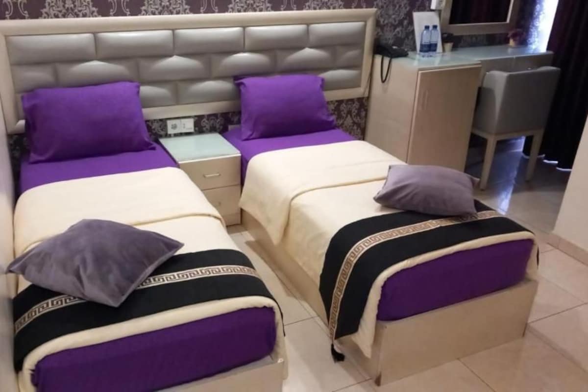Habitación doble con dos camas, cada una con cabecera, mesita de noche y lámpara.