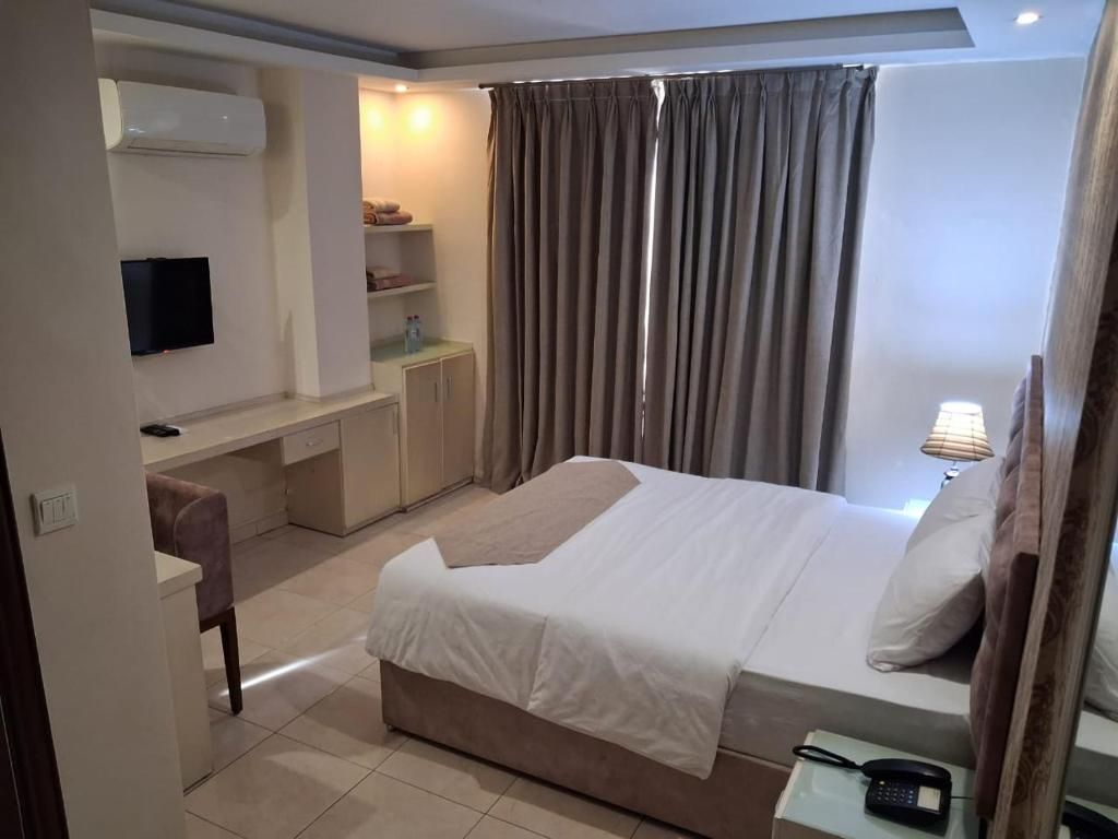 A hotel room with a bed, a desk, a TV, and a bathroom.