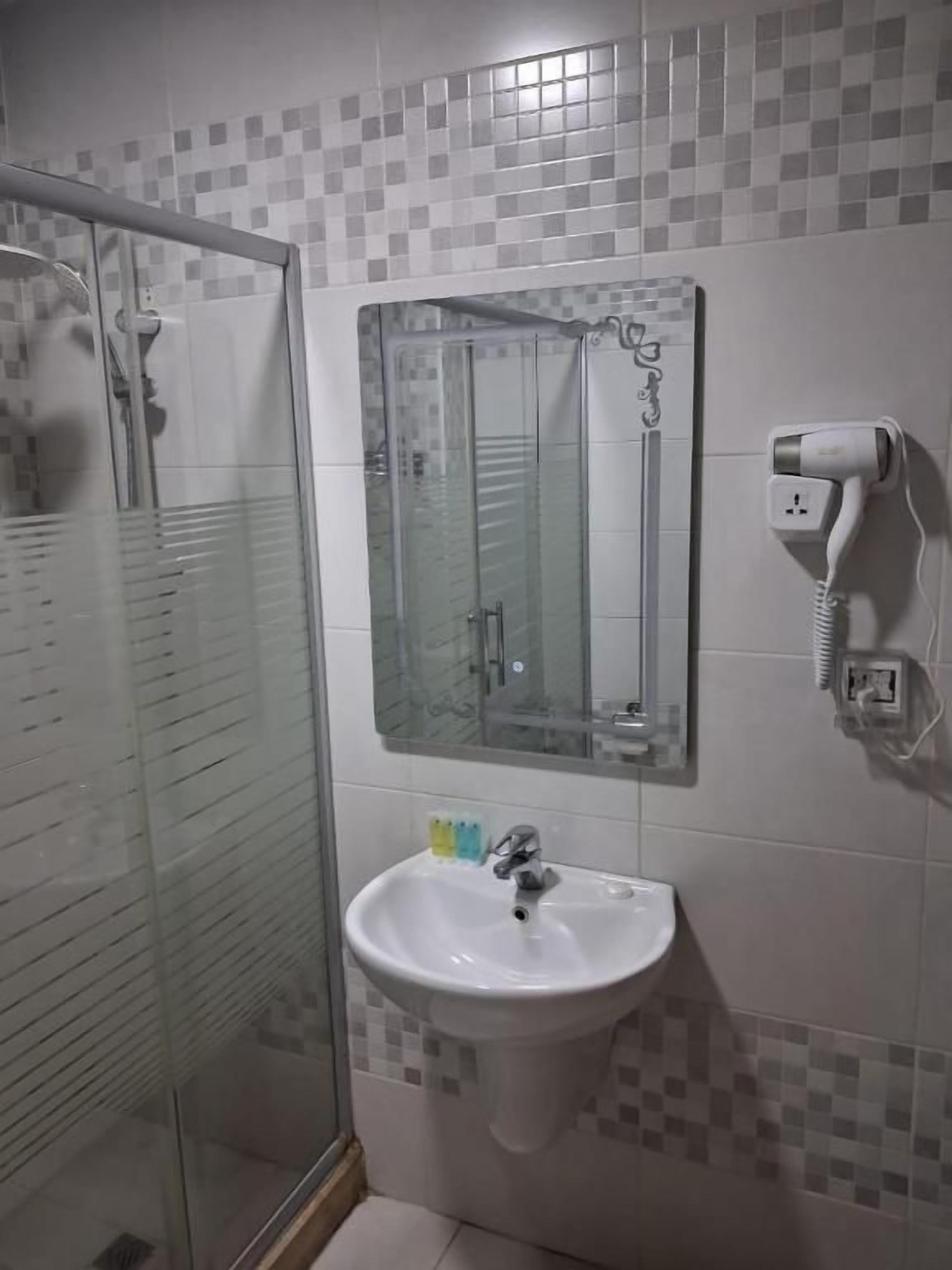 A bathroom with a glass shower enclosure, a white sink, and a mirror.