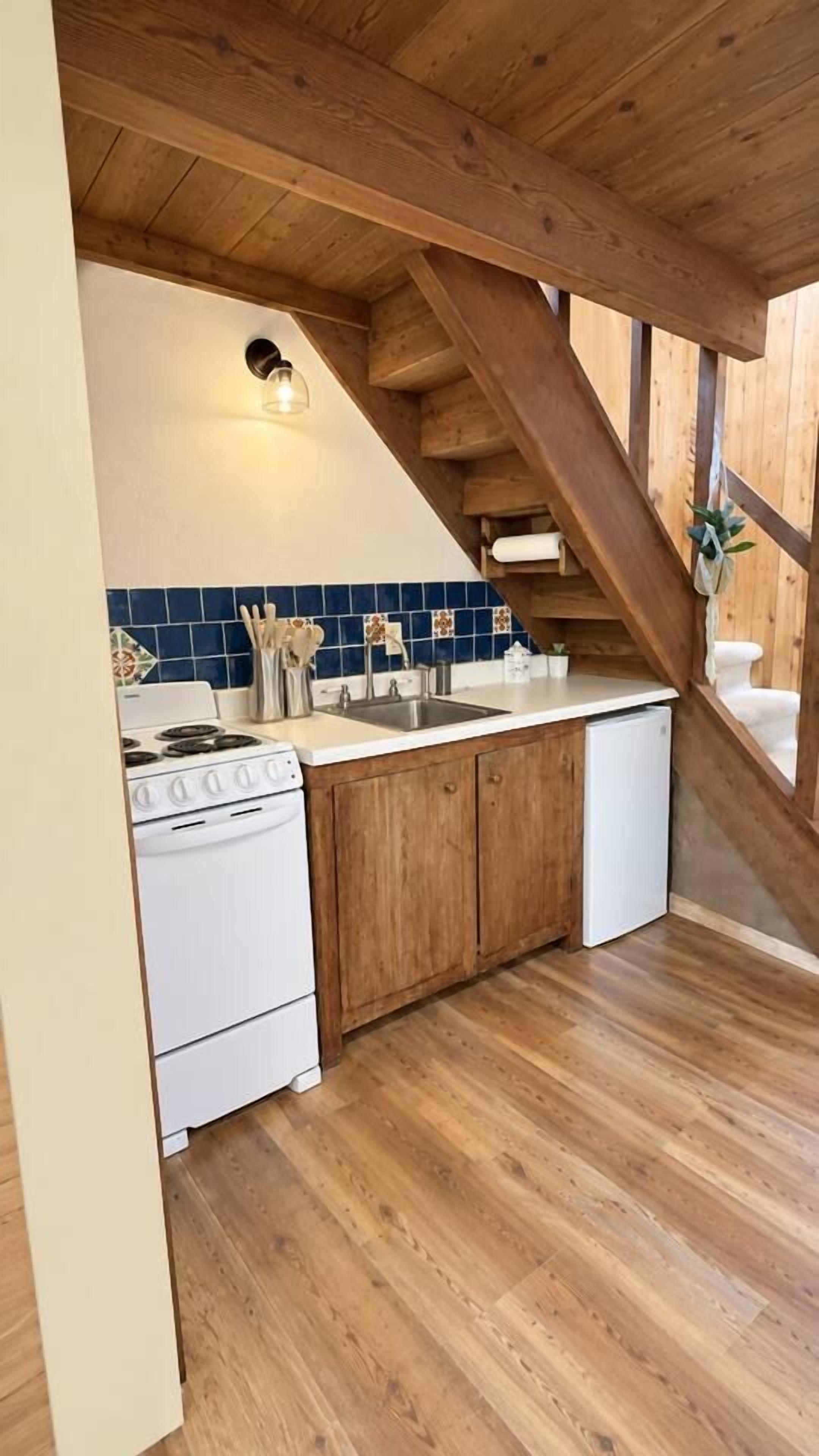 A kitchen with wooden beams, a stove, sink, and cabinets.