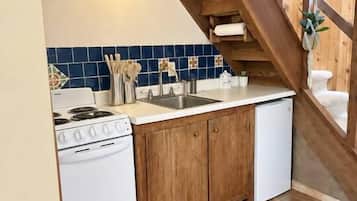 A kitchen with wooden beams, a stove, sink, and cabinets.