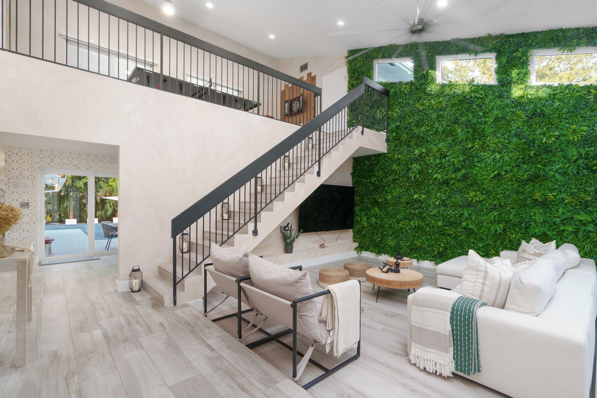 A modern interior with a staircase, a green wall, and a white sofa.