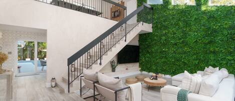 A modern interior with a staircase, a green wall, and a white sofa.