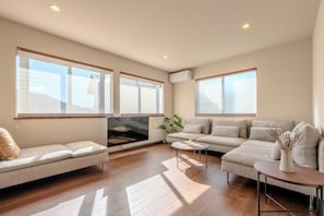 A modern living room with a sectional sofa, a coffee table, and a flat-screen TV. - Oguma (Nozawaonsen)