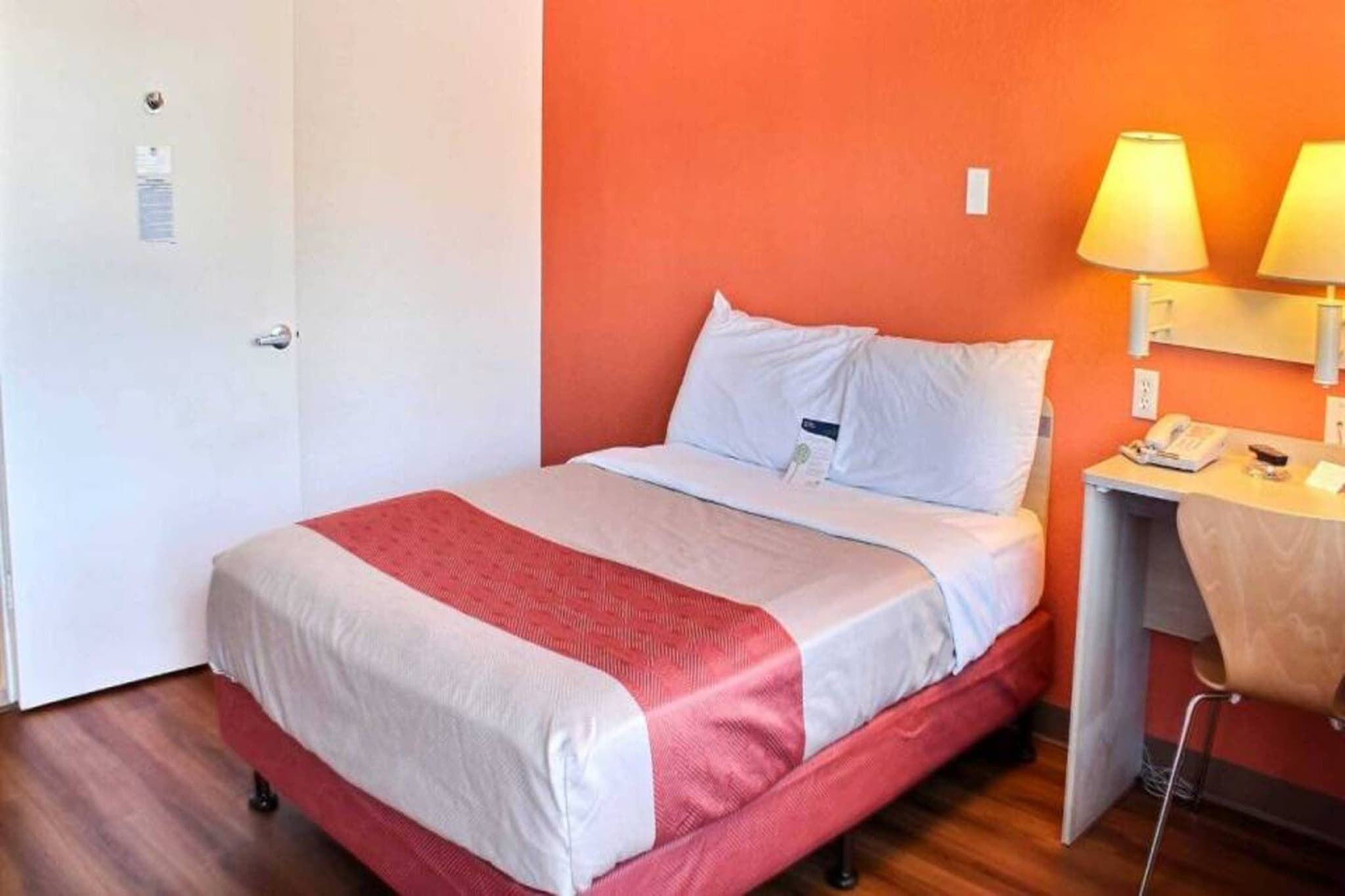 Una habitación de hotel con una cama, un escritorio con lámpara y un teléfono.