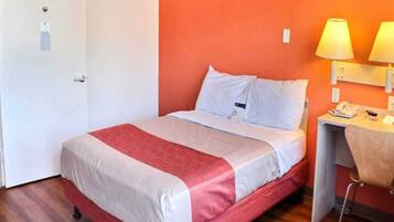 Una habitación de hotel con una cama, un escritorio con lámpara y un teléfono.