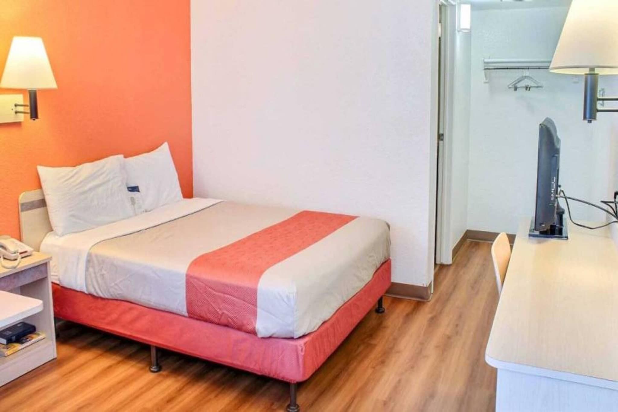 A hotel room with a bed, a bedside table, a lamp, and a television.