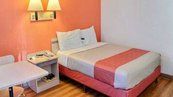A hotel room with a bed, a bedside table with a phone, a small table, and two wall-mounted lamps.