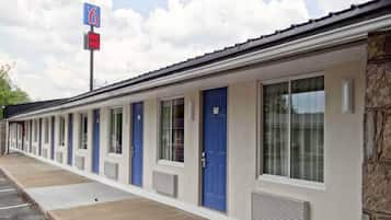 Um motel com uma fileira de quartos, cada um com uma porta azul e uma janela.