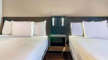 A hotel room with two single beds, a nightstand, and a mirror.
