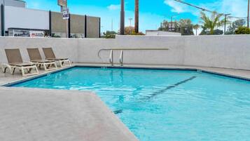 A swimming pool with lounge chairs and a lifeguard stand.