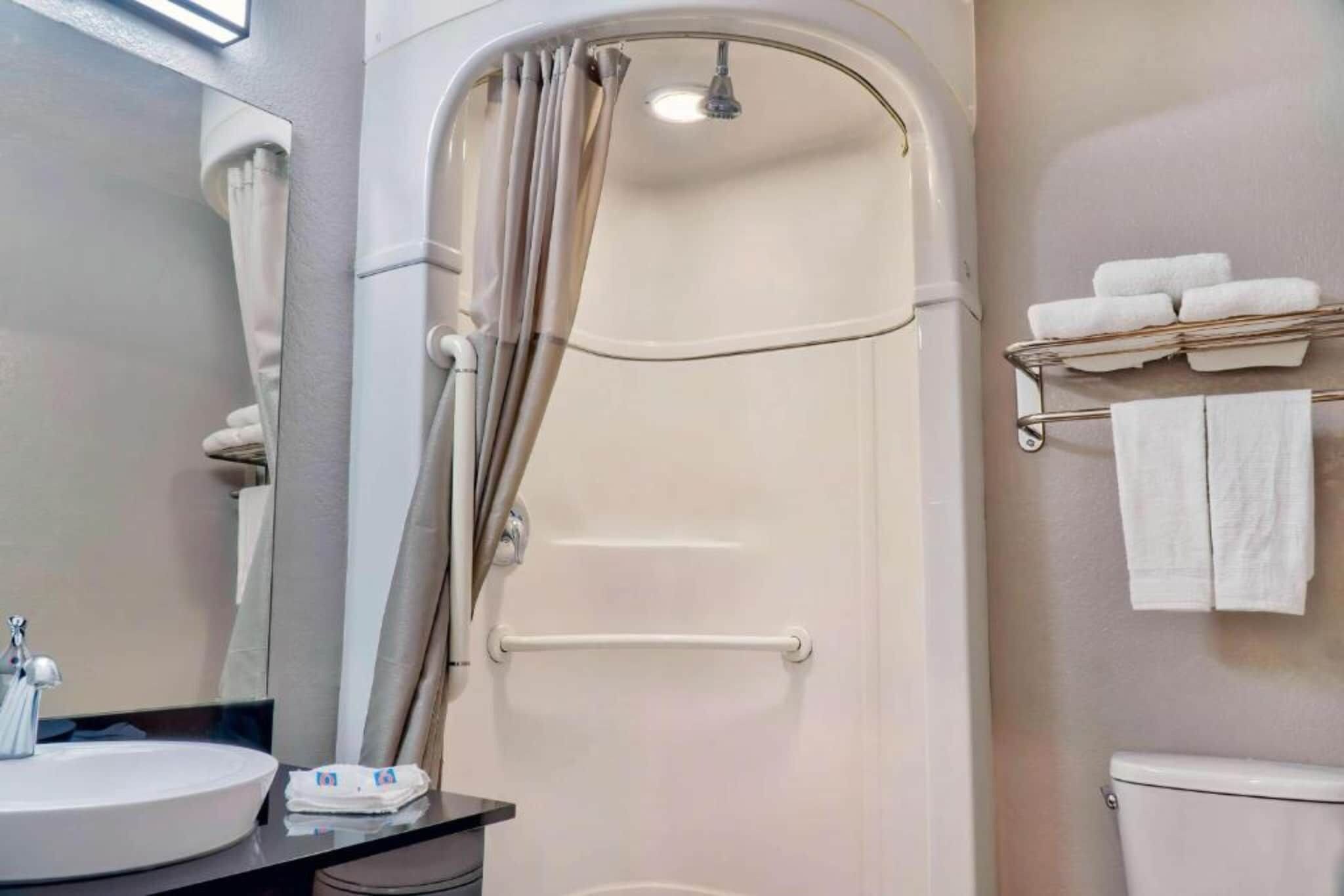 Un baño con ducha, lavamanos y un perchero para toallas.