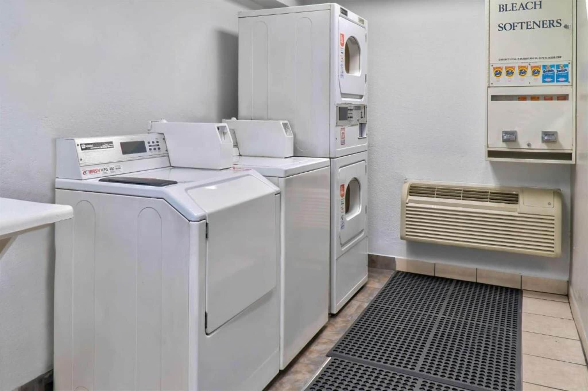 A laundry room with a washing machine, dryer, and a wall-mounted heater.