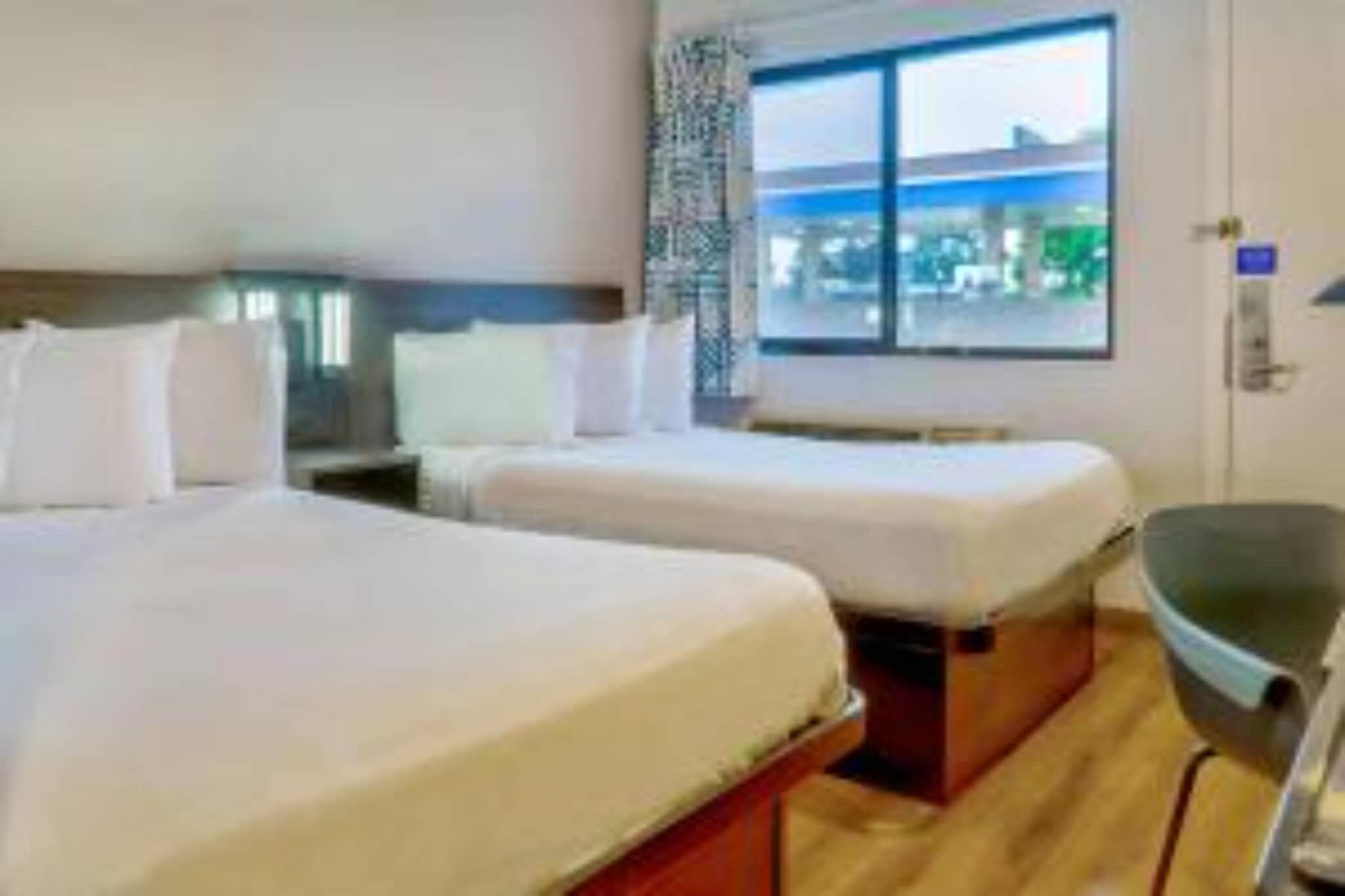 Een hotelkamer met twee bedden, een raam met uitzicht en een stoel.