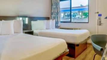 Een hotelkamer met twee bedden, een raam met uitzicht en een stoel.