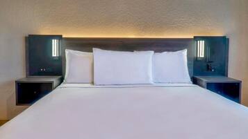 A hotel room with a large bed, two bedside tables, and wall-mounted lighting.