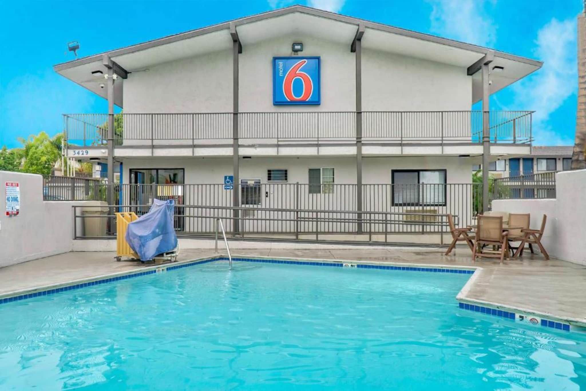 Un motel doté d’une piscine, d’un patio couvert et d’un panneau indiquant le numéro 6.