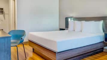 A modern hotel room with a bed, a desk, and a chair.