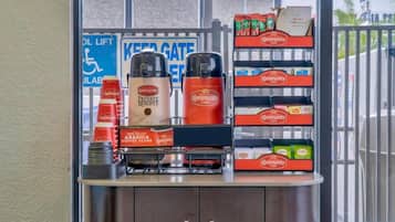 Een koffiehoek met een koffieapparaat, kopjes en koffiebonen.