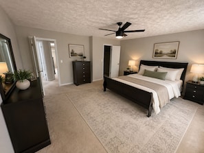 A bedroom with a bed, bedside tables, a dresser, a ceiling fan, and a door leading to another room. - Spacious 4BR Lawrenceville Home (Lawrenceville)