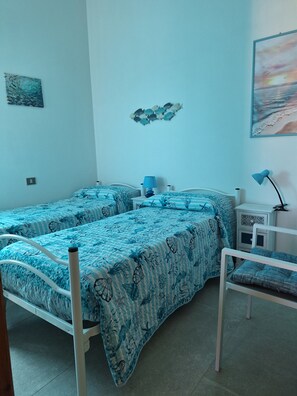 Ein Schlafzimmer mit zwei Betten, einem Nachttisch, einer Lampe und einer Wanddekoration.