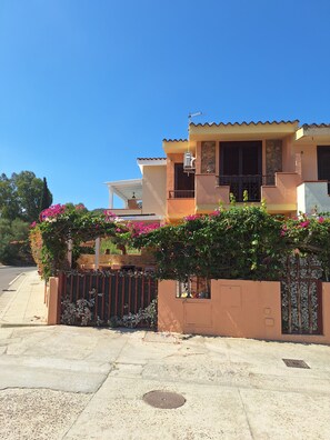 Ein zweigeschossiges Haus mit einem Balkon, einer Steinmauer und einem Metallgitter.