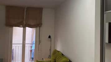 A room with a dining table, a sofa, and a ceiling light fixture.