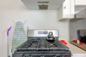 A kitchen with a gas stove, a kettle, and a wall-mounted rack. - LA Home w/ Porch, 3 Mi to Stadiums! (Los Angeles)