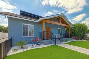 A modern house with a covered porch, a solar panel, and a well-maintained lawn. - LA Home w/ Porch, 3 Mi to Stadiums! (Los Angeles)