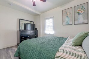 A bedroom with a bed, dresser, mirror, artwork, and a window with blinds. - LA Home w/ Porch, 3 Mi to Stadiums! (Los Angeles)