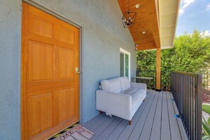 A wooden door, a white sofa, and a wooden deck with a railing. - LA Home w/ Porch, 3 Mi to Stadiums! (Los Angeles)