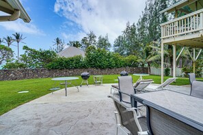 Eine Terrasse im Freien mit Grill, Liegestühlen und einer Steinmauer.