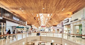 Ein geräumiges Einkaufszentrum mit modernem Holzbalken-Design und zahlreichen Geschäften.